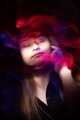 Portrait of young woman amid light painting , Over Black Background. Long exposure photo without photoshop, light drawing at long exposure