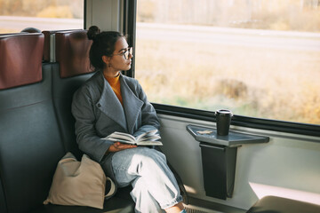 Young beautiful girl on a train reading a book while traveling in a train