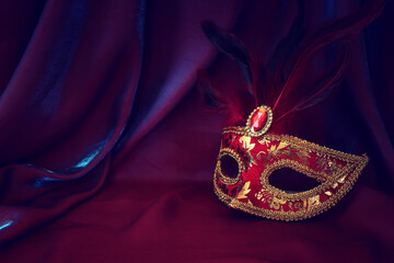 Photo of elegant and delicate Venetian mask over red silk background