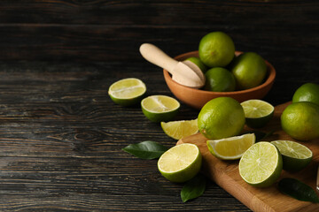 Bowl and board with lime on wooden background, space for text