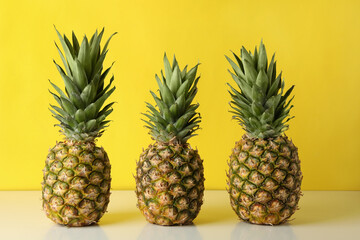 Three tasty ripe pineapples against yellow background