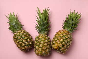 Three tasty ripe pineapples on pink background