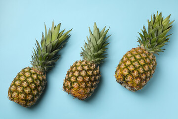 Fototapeta premium Three tasty ripe pineapples on blue background