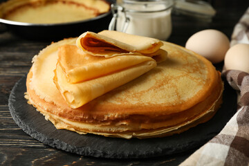 Concept of tasty breakfast with thin pancakes on wooden table