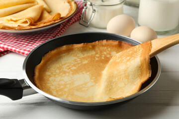 Concept of tasty breakfast with thin pancakes on white wooden table