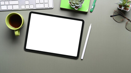 Top view of mock up digital tablet, stylus pen and coffee cup on green background.
