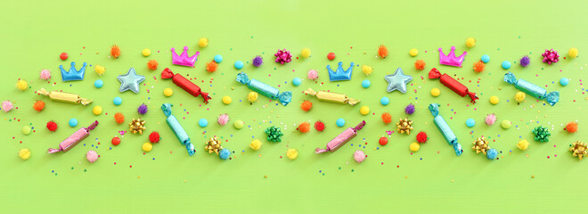 Party colorful confetti and candies over green wooden background . Top view, flat lay