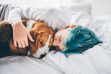 Sad boy with dog laying at the bed. 