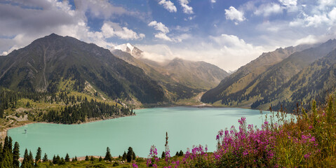 Amazing panorama of Big Almaty Lake on sunny summer day with cloudy sky, Kazakhstan nature.