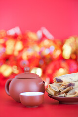 A plate of spring fried rolls and teapots and bowls on a red background