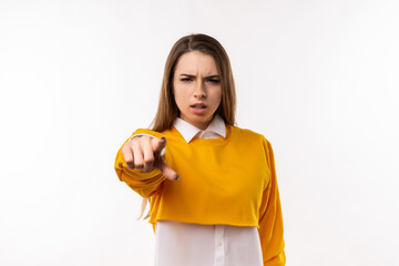 Fototapeta na wymiar Displeased young brunette woman is pointing finger at camera, angry and furious with you. Studio shot, white background