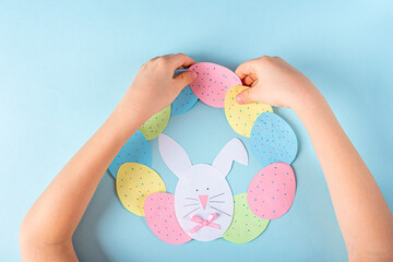 DIY and kids creativity. Step by step instruction: how to make paper easter wreath. Step9 glue paper eggs and bunny to circle like wreath. Childrens handmade Easter craft.