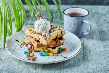 Waffles with ice-cream, chocolate, M$M's on the white plate with tea