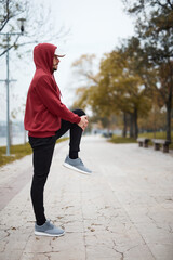 Fototapeta premium Athletic sporty man training in hoodie sweatshirt in urban city park.