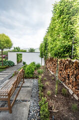 Nowoczesna biała ścianka w ogrodzie jako wejście do warzywnika dzieląca ogród na dwie części