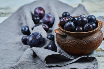 Garden plums in a bowl on gray tablecloth