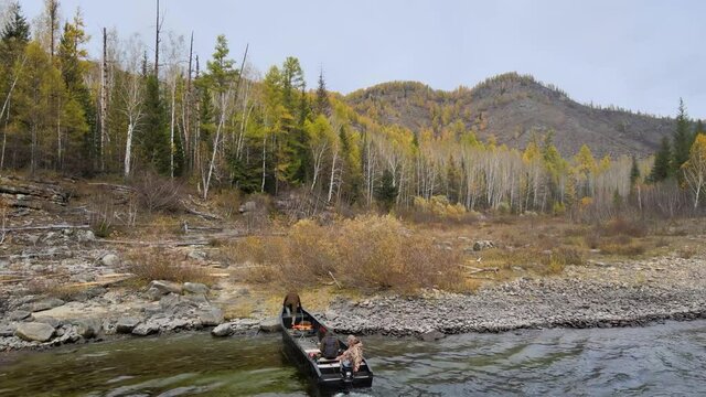 the boat moors to the shore, a man with a rope moors the boat on the shore, Republic of Tuva, Russia