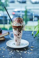 Milkshake with cone, chocolate , sprinkles and books in the dark background