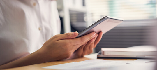 Businesswoman holding tablet and used to work online on the table at office.