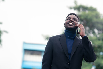 Handsome african business man using smartphone in trendy formal black suit. Guy with beard wearing blue long sleeve or sweater