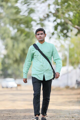 Young Indian male model standing and holding the office bag and giving expression.