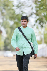Young Indian male model standing and holding the office bag and giving expression.