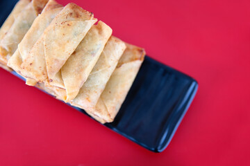 Overlooking a dish of fried spring rolls on a red background
