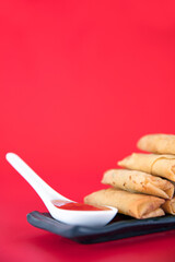 Fried spring rolls and dips on a red background