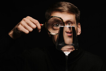 portrait of a man looking through a magnifying glass and a glass of water