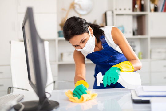 Female cleaner working in protective mask productively on task in office