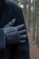 Hand in black leather glove touching shoulder in black coat.