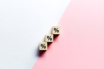 Wooden blocks stacking as step stair with percent or percentage symbol on pink and white...