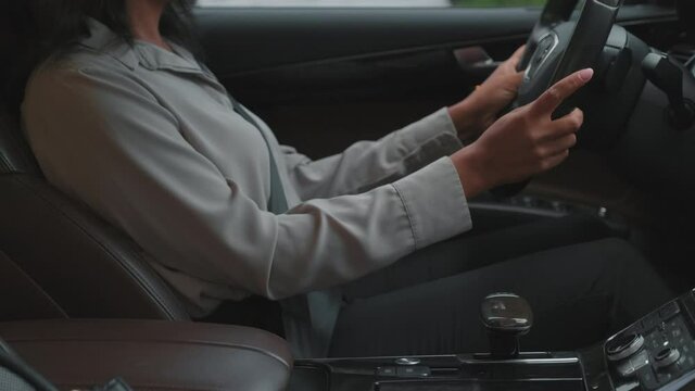 Midsection footage of unrecognizable business-like woman sitting in drivers seat and fastening seatbelt