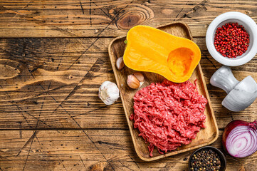 Cooking pumpkin with mince meat, garlic and onion. Wooden background. Top view. Copy space