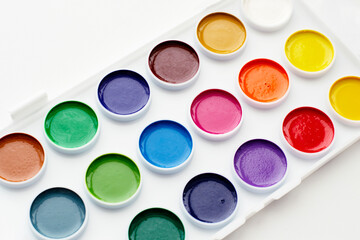 Watercolour paints and a palette on a white background.