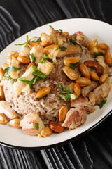 Lebanese spiced ground beef and rice are served with toasted nuts and shredded juicy chicken closeup in the plate on the table. vertical