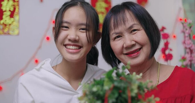 Asian Senior Woman And Niece Decorate House For Chinese New Year Celebrations. Text On The Wall Means Lucky And Healthy.