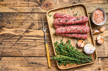 Homamade raw mince meat  sausages on a cutting board. wooden background. Top view. Copy space
