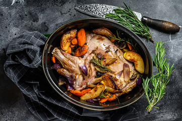 Baked whole lamb shoulder leg in a baking dish.  Black background. Top view