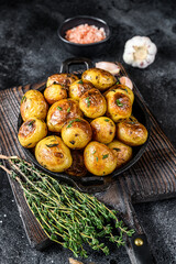 Baked youg potato with thyme in a pan Black background. Top view