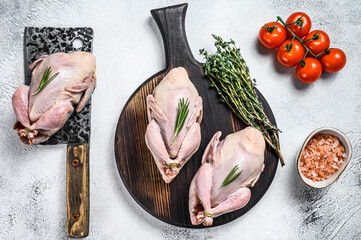 Raw quails preparation on a wooden cutting board with meat cleaver. White background. Top view - obrazy, fototapety, plakaty