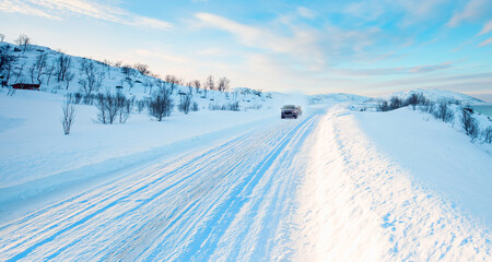 Fototapeta na wymiar SUV rides on a winter forest road - A car in a snow-covered road among trees and snow hills