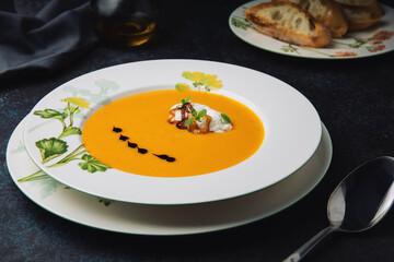 Pumpkin cream soup with onion, herbs, ricotta cheese, pumpkin oil and roasted baguette. Vegetarian food.