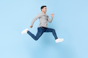Smiling handsome man jumping in light blue color isolated studio background