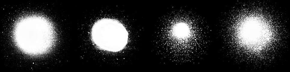 Close-up of several white spray paint spots and splashes, isolated on black background.
