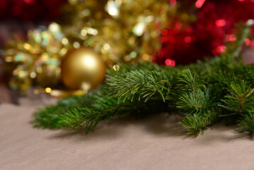 Winter background for New Year and Christmas, fir branches, tinsel, Christmas tree decoration, orange beads, blurry lights.