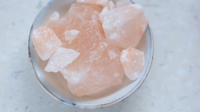 Pink himalayan salt in a gray cup on a  marble background.Pink crystal salt