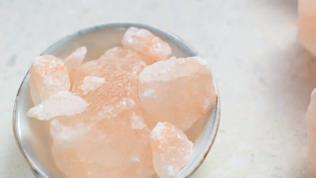 Pink himalayan salt pieces close-up in a gray cup on a  marble background.Pink crystal salt