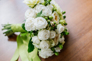 Beautiful wedding bouquet and rings on wooden background