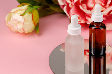 Glass bottle with oil on round mirror on pink background